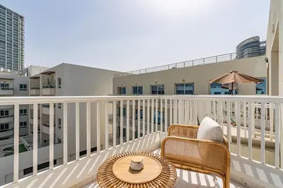 a balcony with a chair and a table and an umbrella at Chic Studio in JVC near Stadium and Miracle Garden in Dubai
