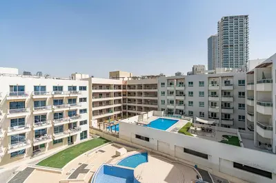 an apartment complex with a swimming pool and buildings at Chic Studio in JVC near Stadium and Miracle Garden in Dubai