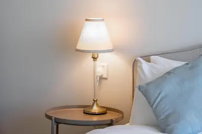 a lamp sitting on a table next to a bed at Dubai Business Bay Modern Cozy Studio with Skyline Views & Lagoon Pool Access in Dubai