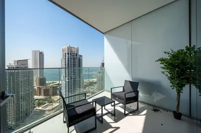 a balcony with two chairs and a table with a view at Homes Beyond l Marina Luxe 1BR at LIV in Dubai