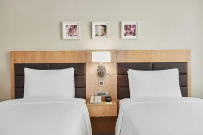 two beds in a hotel room with white sheets at Hilton Garden Inn Dubai, Mall Avenue in Dubai