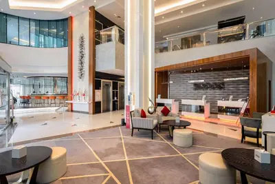 a lobby with tables and chairs in a building at Ramada by Wyndham Dubai Barsha Heights in Dubai