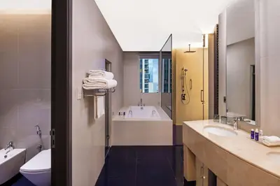 a bathroom with two sinks and a tub and a toilet at V Hotel Dubai, Curio Collection by Hilton in Dubai