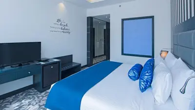 a bedroom with a bed with blue pillows and a television at Signature 1 Hotel Tecom in Dubai