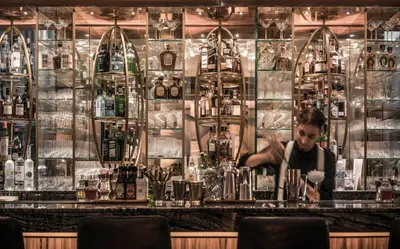 a bartender behind a bar with bottles of alcohol at Four Seasons Hotel Dubai International Financial Centre in Dubai