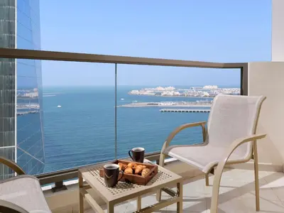 a room with a table and chairs and a view of the ocean at Mövenpick Hotel Jumeirah Beach in Dubai