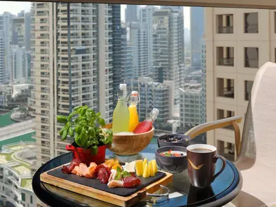 a tray of food on a table with a view of a city at Mövenpick Hotel Jumeirah Beach in Dubai