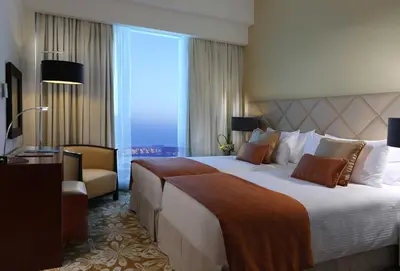 a hotel room with a large bed and a chair at La Suite Dubai Hotel & Apartments in Dubai