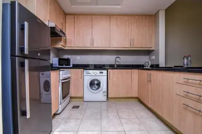 a kitchen with wooden cabinets and a washer and dryer at Parkside Hotel Apartment in Dubai
