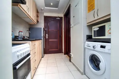 a small kitchen with a washer and dryer at Parkside Hotel Apartment in Dubai