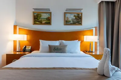 a bedroom with a large white bed with two lamps at Grand Bellevue Hotel Apartment Dubai in Dubai