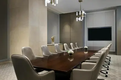 a conference room with a wooden table and white chairs at Kempinski Central Avenue Dubai in Dubai