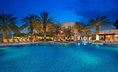 a large swimming pool with palm trees and a building at Address Montgomerie in Dubai