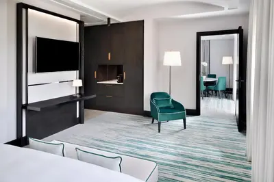 a hotel room with a bed and a green chair at Address Montgomerie in Dubai