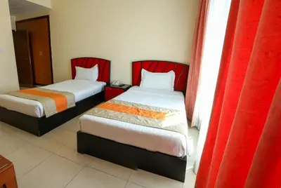 two beds in a room with red curtains at Wescott Plaza Hotel Apartments LLC Formerly West Zone Plaza Hotel Apts in Dubai