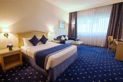 a hotel room with a large bed and a chair at Capitol Hotel Jumeirah Dubai in Dubai
