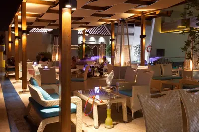 a restaurant with chairs and tables and a cat sitting on a table at Capitol Hotel Jumeirah Dubai in Dubai
