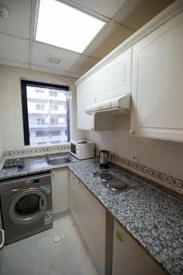 a kitchen with a washing machine and a window at Welcome Hotel Apartments 1 in Dubai