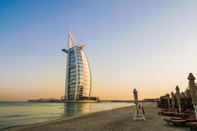 a burj al arab hotel on the beach at sunset at Naumi Hotel Dubai in Dubai