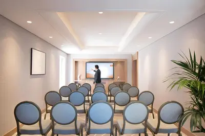 a meeting room with a man standing in front of a screen at Naumi Hotel Dubai in Dubai
