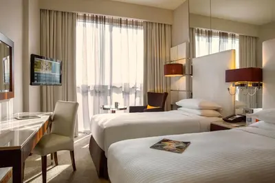 a hotel room with two beds and a desk at Centro Barsha - by Rotana in Dubai
