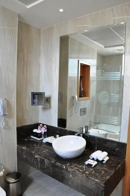a bathroom with a sink and a large mirror at Fortune Park Hotel in Dubai