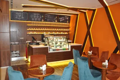 a restaurant with tables and chairs and a counter at Fortune Park Hotel in Dubai