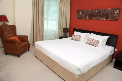 a bedroom with a large bed and a chair at Armada Living - Holiday Homes Rental in Dubai