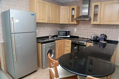a kitchen with a refrigerator and a table in it at Armada Living - Holiday Homes Rental in Dubai