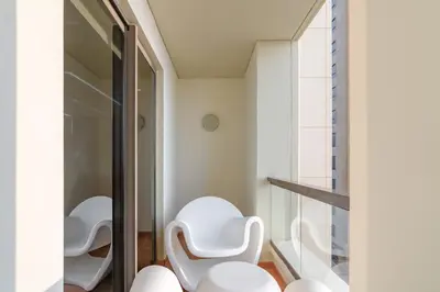 a bathroom with white chairs and a glass door at Elan Rimal Suites in Dubai