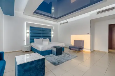 a bedroom with a bed and a blue headboard at Elan Rimal Suites in Dubai