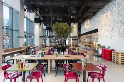 a restaurant with wooden tables and red chairs at Rove Bur Dubai - Healthcare City in Dubai