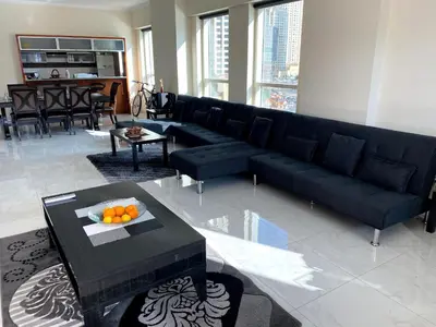 a living room with a black couch and a table at My-Places Dubai Apartment suitable for large groups Al Sahab 1 in Dubai