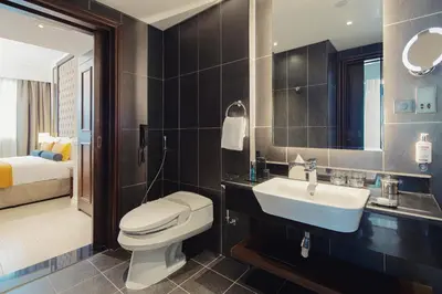 a bathroom with a toilet and a sink and a mirror at Dukes The Palm Dubai Hotel in Dubai