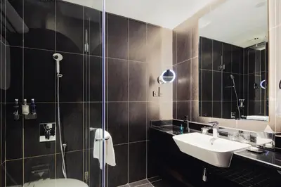 a bathroom with a sink and a shower at Dukes The Palm Dubai Hotel in Dubai