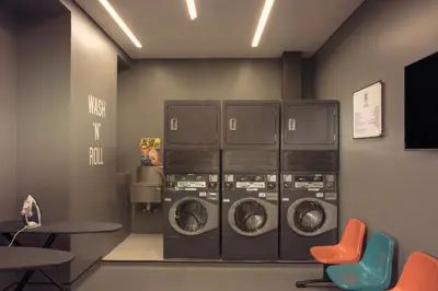 a laundry room with four washing machines and two tables and chairs at Rove Trade Centre in Dubai
