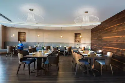 a restaurant with tables and chairs and a person in the background at Radisson Blu Hotel, Dubai Waterfront in Dubai