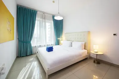 a bedroom with a large white bed with blue curtains at New Arabian 29 Boulevard Downtown in Dubai