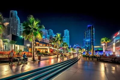 a city street at night with palm trees and buildings at Elan Rimal2 Suites in Dubai