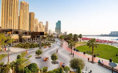 a park in a city with people sitting on benches at Elan Rimal2 Suites in Dubai