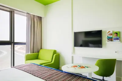a living room with a green chair and a tv at Park Inn by Radisson Dubai Motor City in Dubai