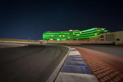 a building with green lights on the side of a race track at Park Inn by Radisson Dubai Motor City in Dubai