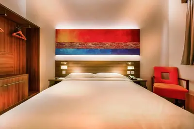a bedroom with a large bed and a red chair at Citymax Hotel Al Barsha at the Mall in Dubai