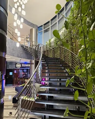 a spiral staircase in a building with green plants at Montreal Barsha Hotel in Dubai