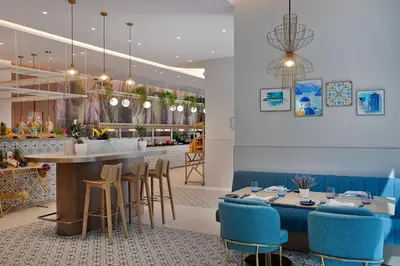 a restaurant with a bar with blue stools at Residence Inn by Marriott Sheikh Zayed Road, Dubai in Dubai