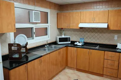 a kitchen with wooden cabinets and a sink and a microwave at Baity Hotel Apartments in Dubai