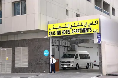 a man standing under a sign in front of a van at Akas-Inn Hotel Apartment in Dubai