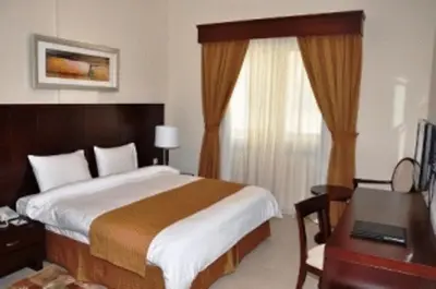 a bedroom with a bed and a desk and a window at Akas-Inn Hotel Apartment in Dubai