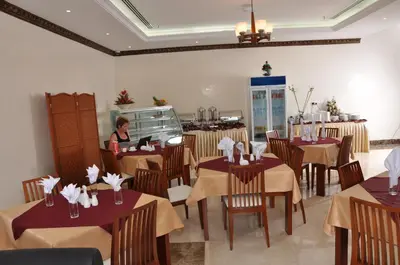 a woman sitting at a table in a restaurant at Akas-Inn Hotel Apartment in Dubai