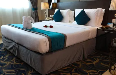 a bed in a hotel room with a teddy bear on it at Omega Hotel Dubai in Dubai